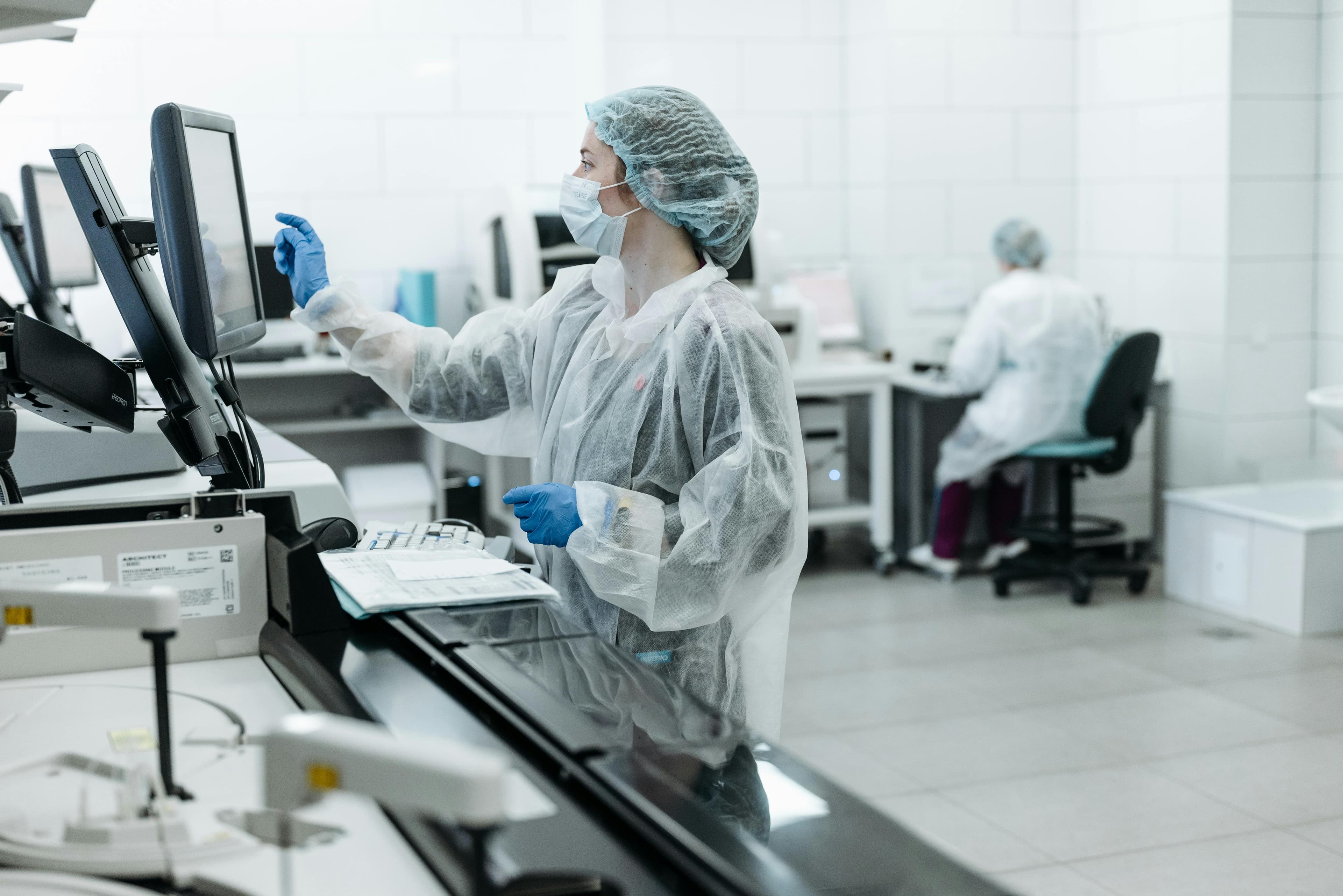 A lab technician wearing PPE works on analysis in a medical laboratory