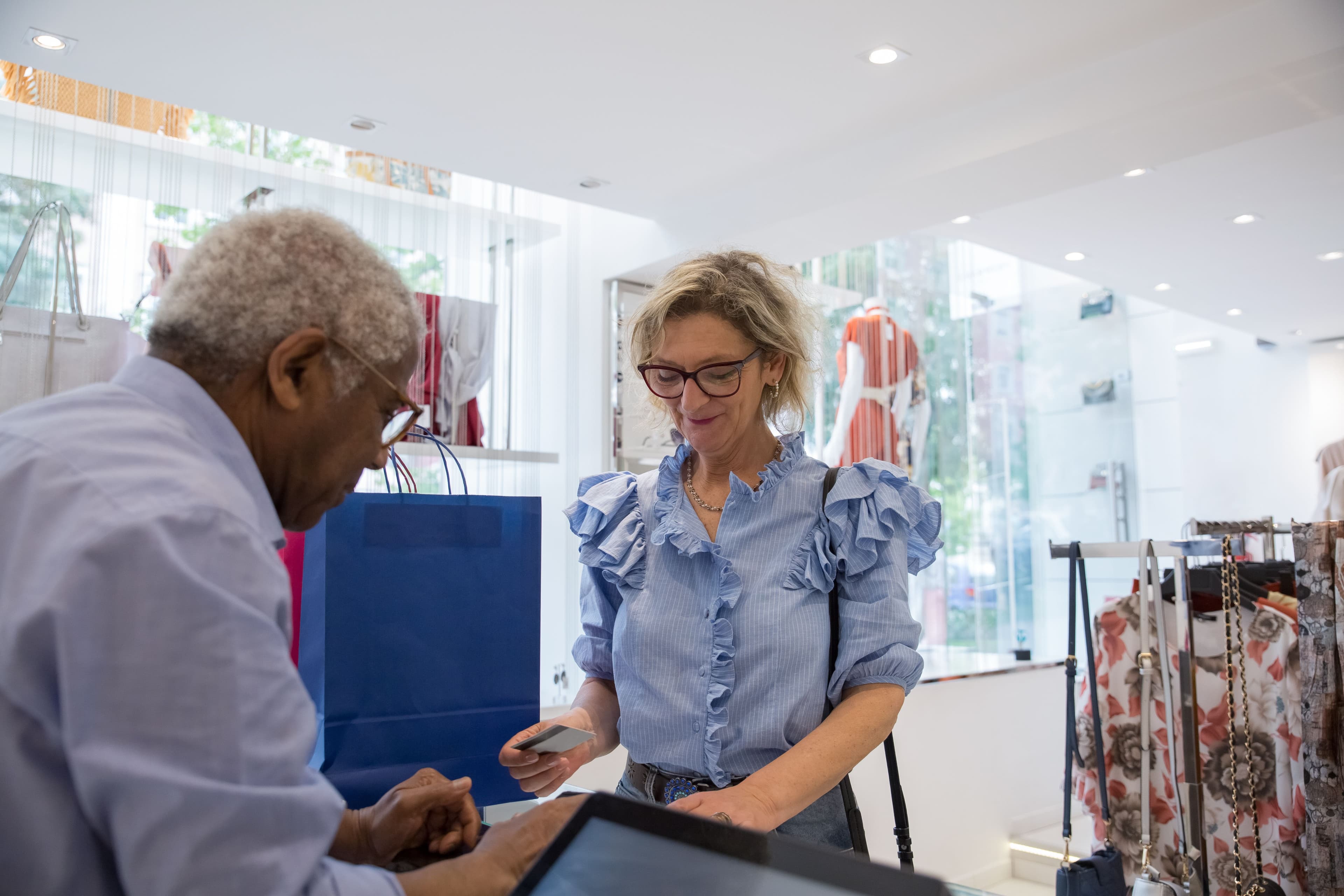 Seniors making a cashless payment in a stylish clothing store