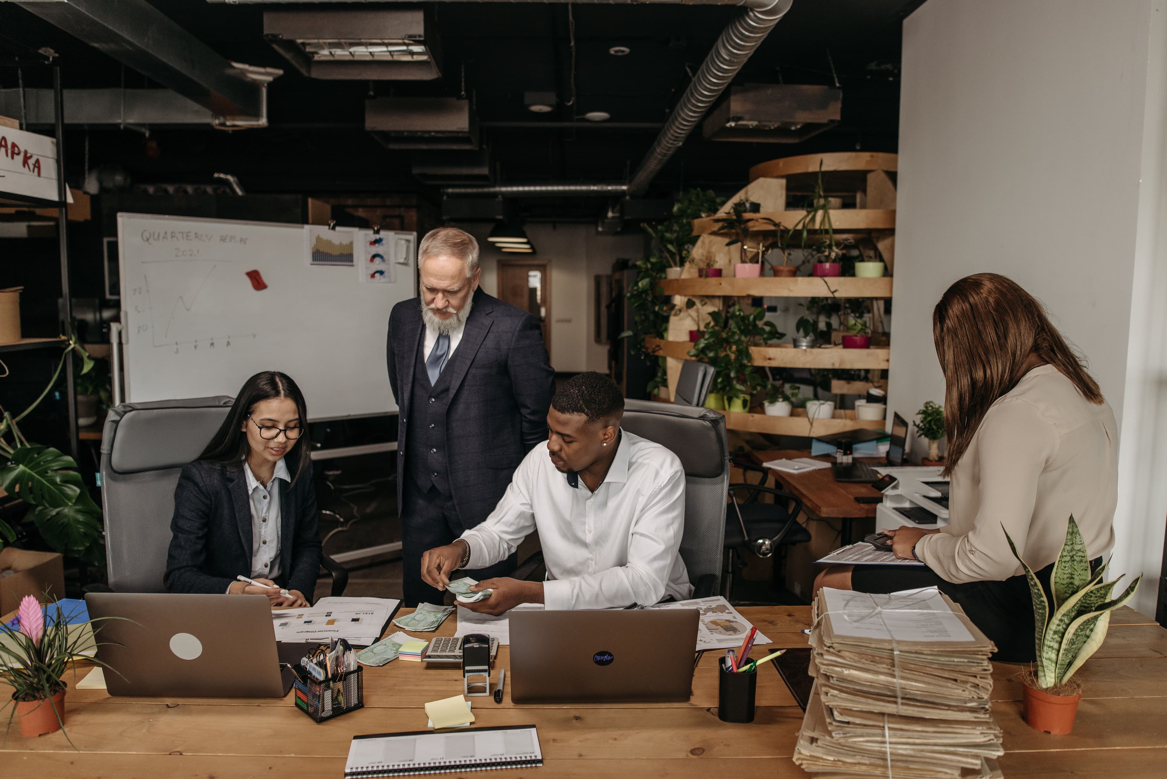 Colleagues working together in a contemporary office setting, counting money and discussing