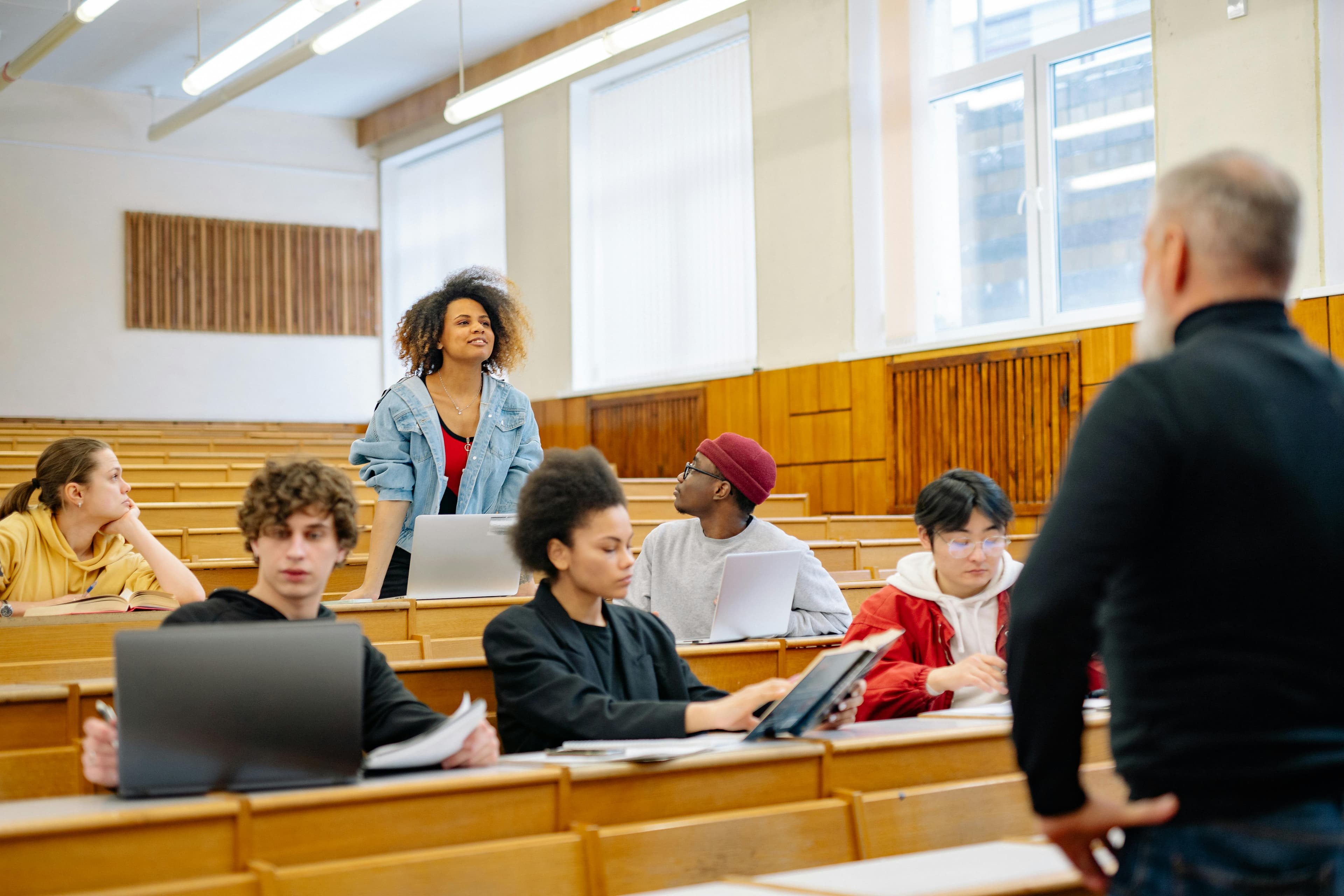 A diverse group of university students actively participating in a lecture, engaging with the professor