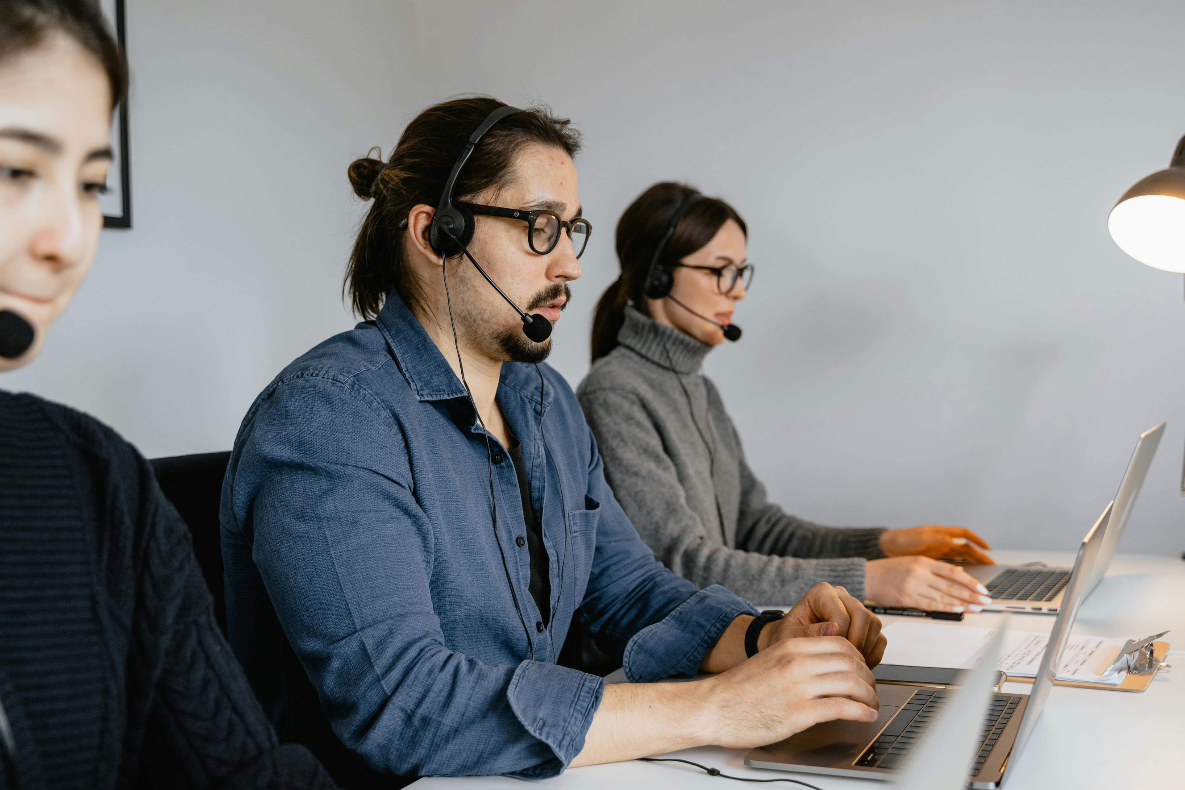 Customer service team at call center using laptops and headsets