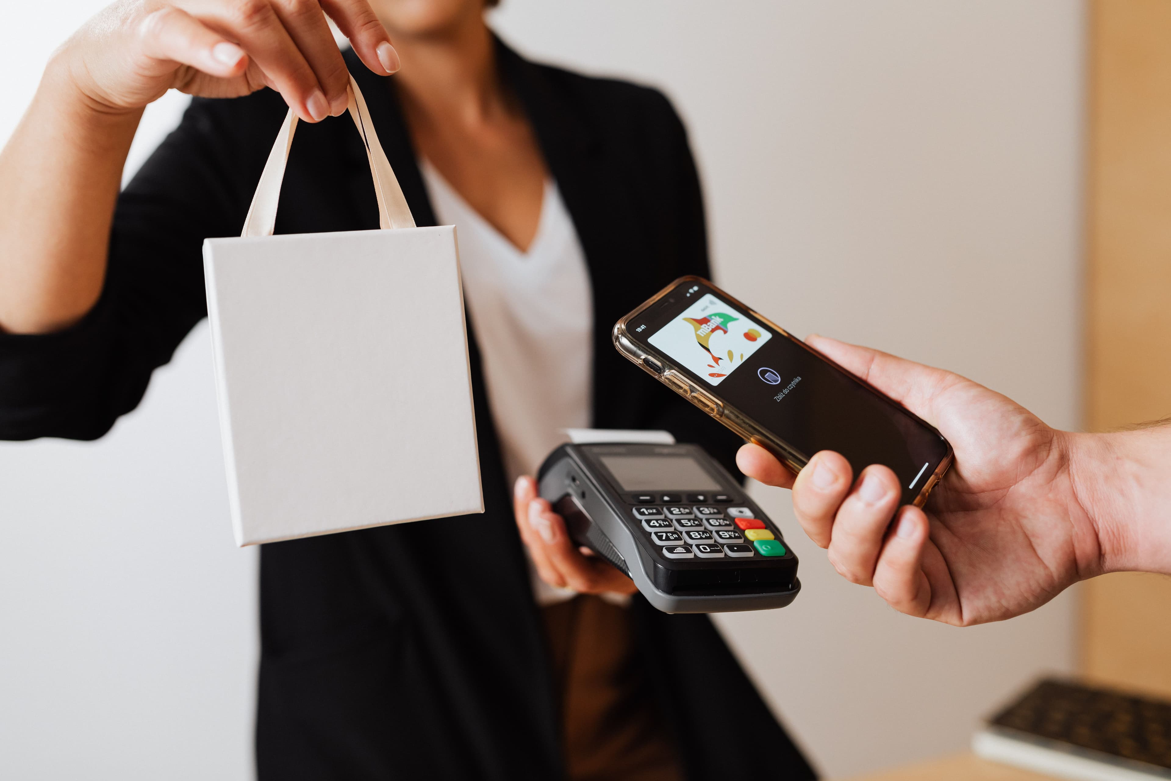 A person uses a smartphone for contactless payment with a payment terminal
