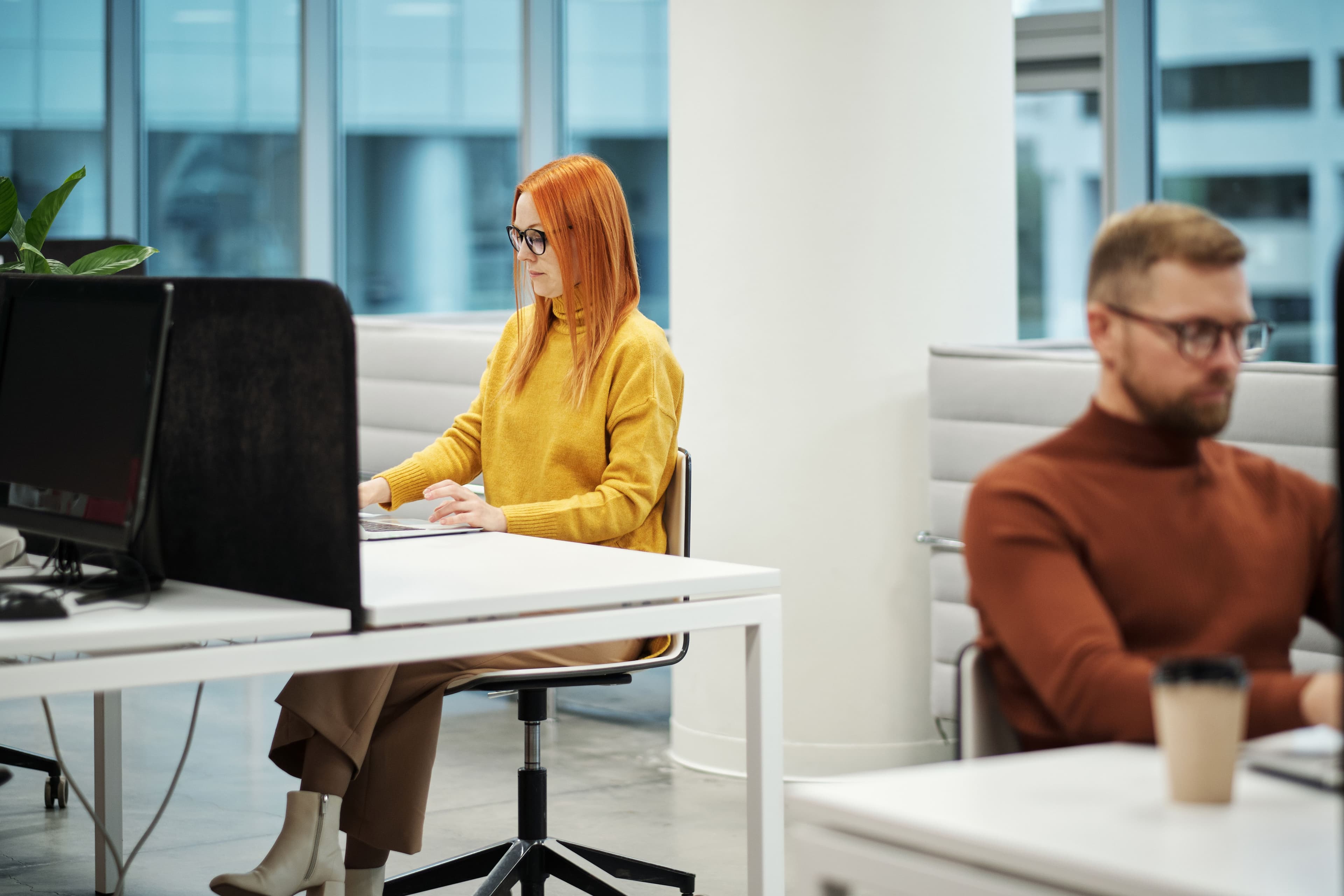 Two professionals working in a contemporary office environment with computers and casual attire