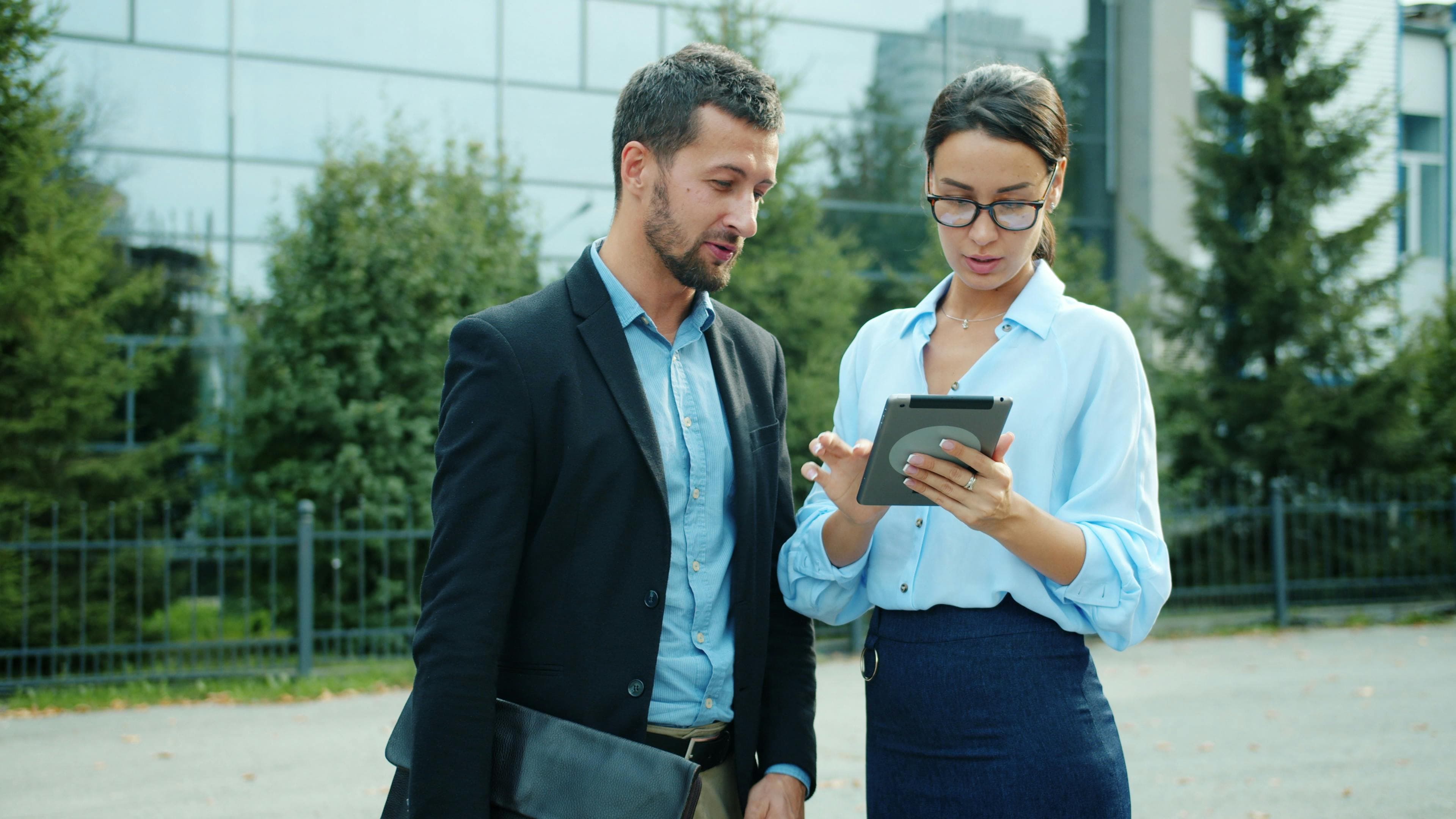 A businessman and businesswoman looking at a tablet outdoors