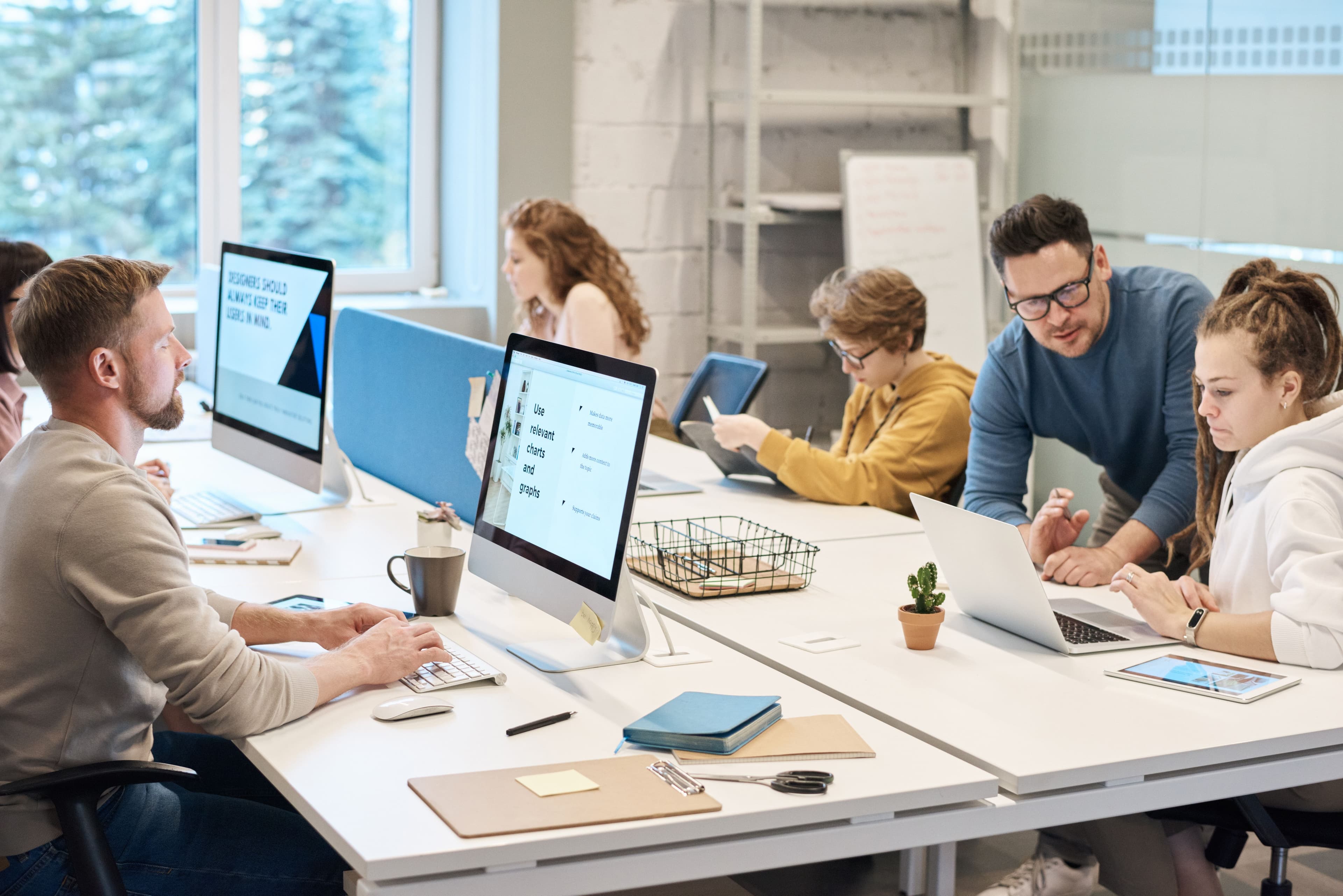 Team collaboration in a modern office setting with computers and diverse employees