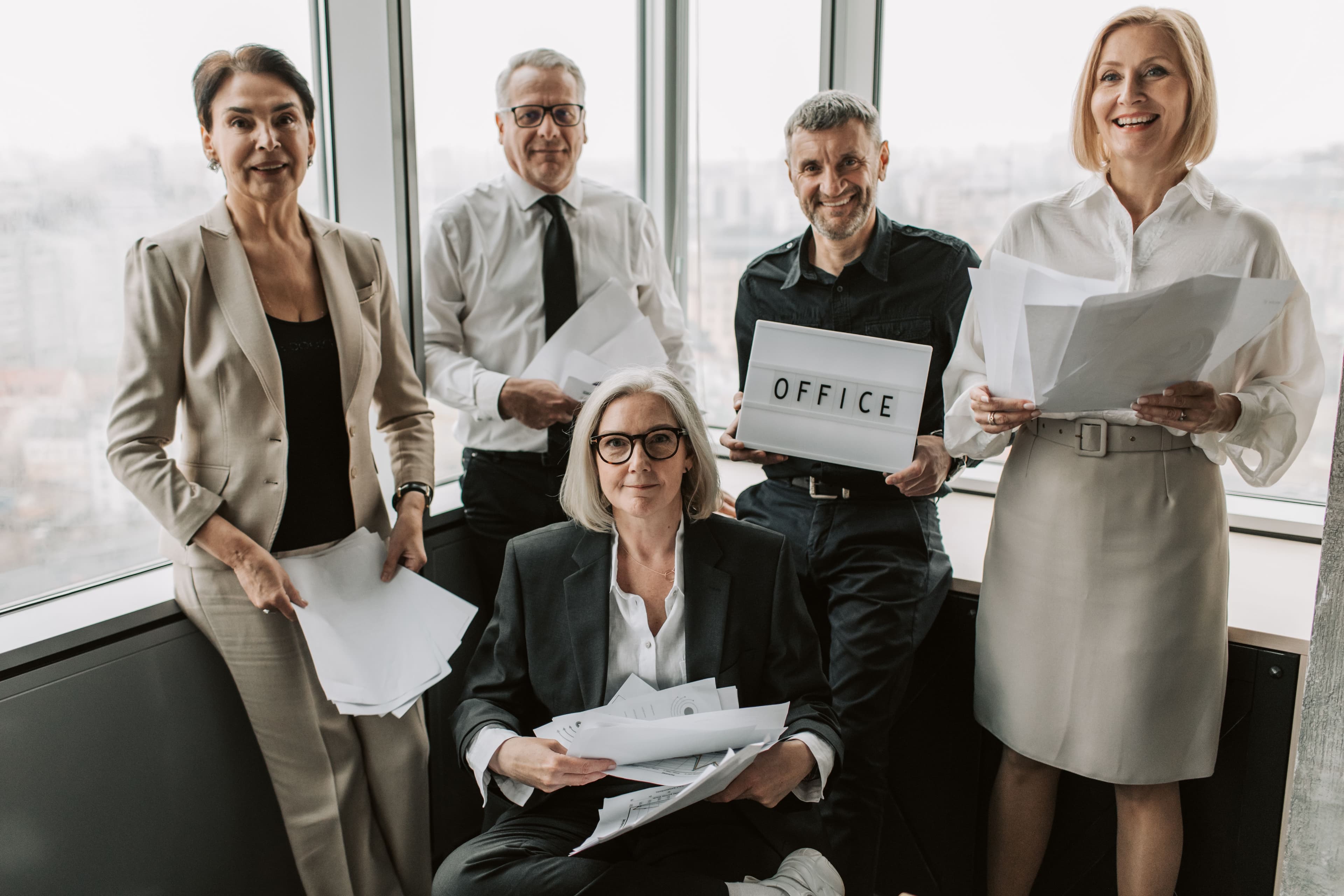 Five colleagues happily collaborating with documents in a modern office