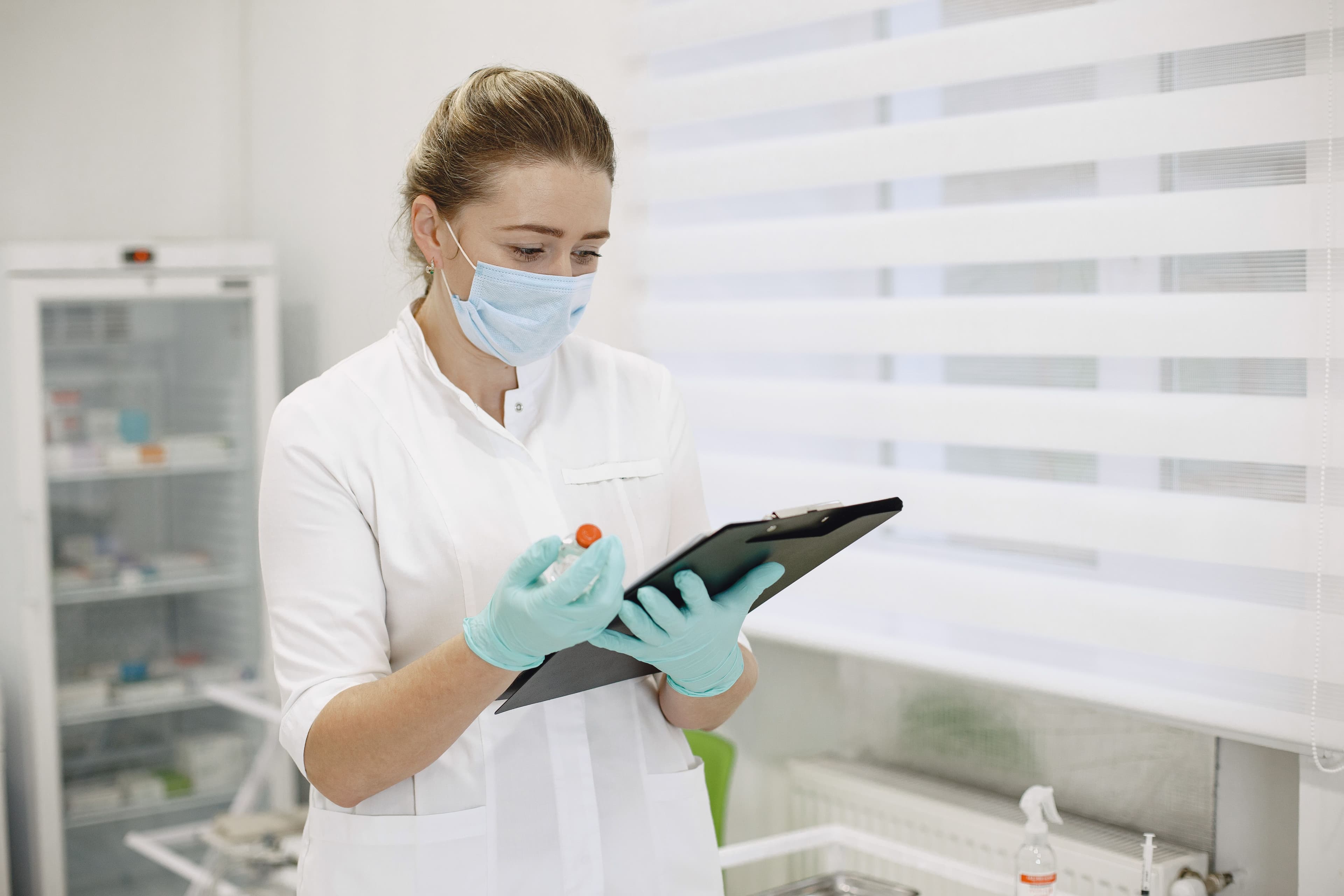 Medical professional in a clinic reviewing patient records while wearing protective gear