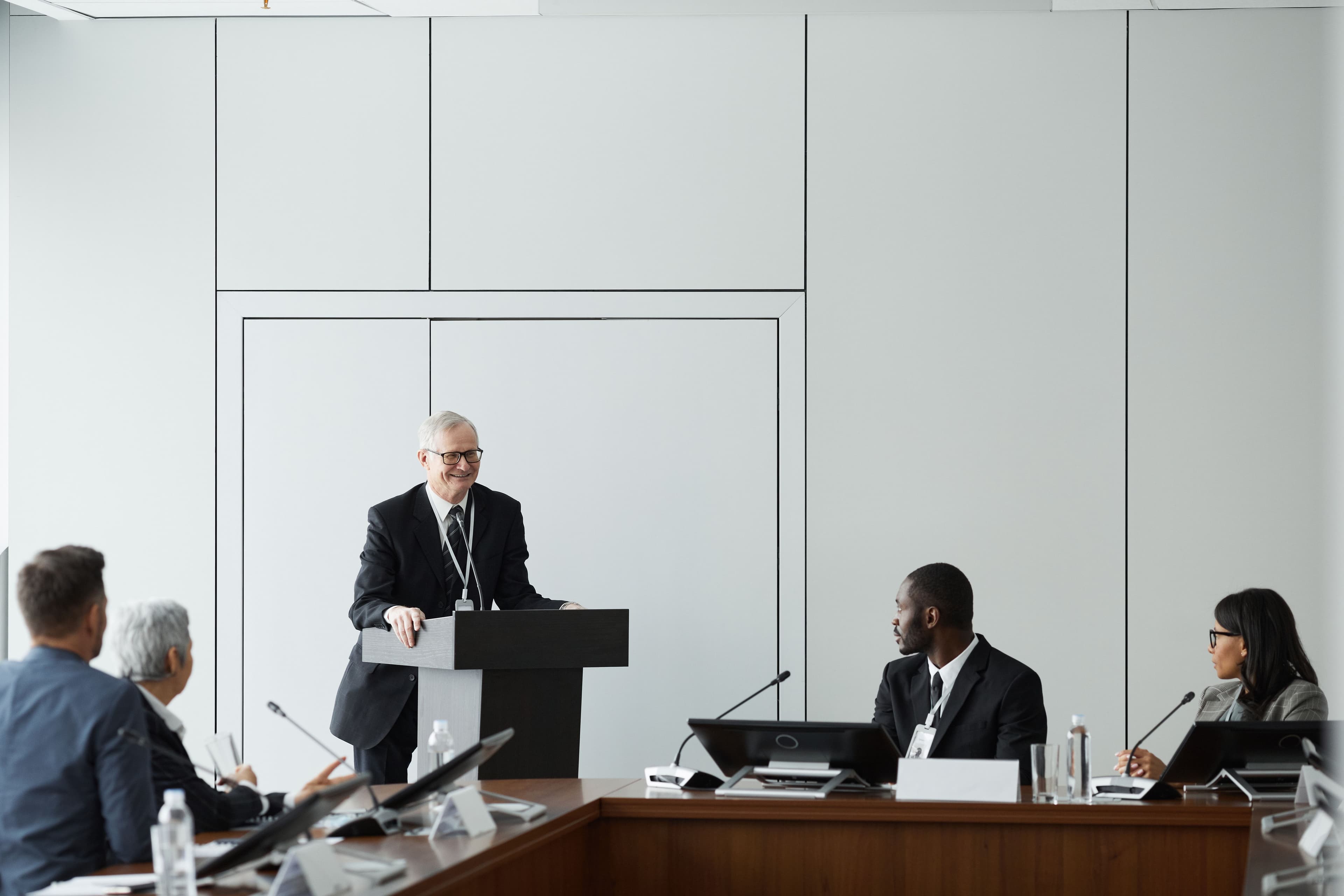Formal business meeting with a diverse group and speaker at a podium in a conference room