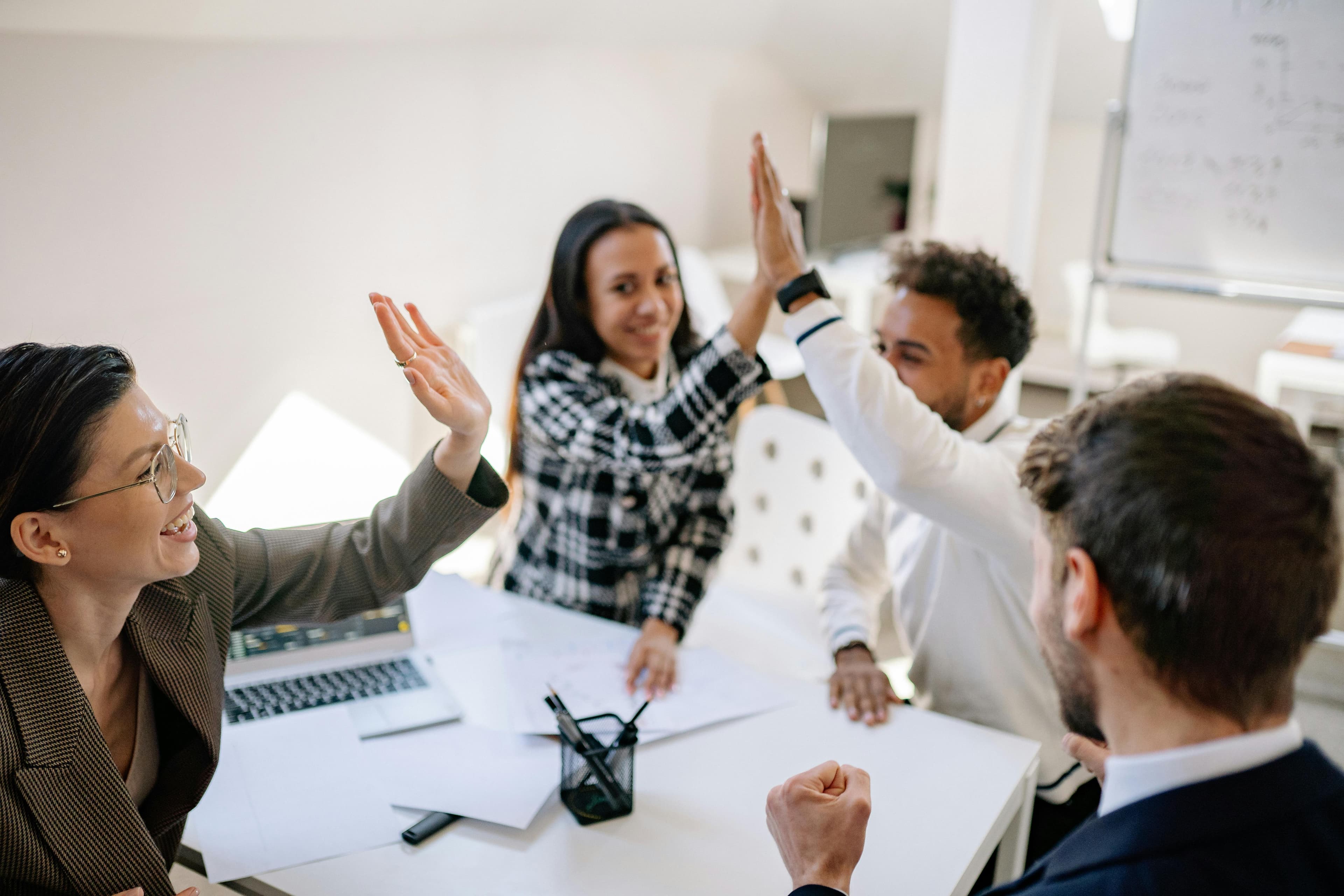 Group of people giving each other high fives while gathered around a table